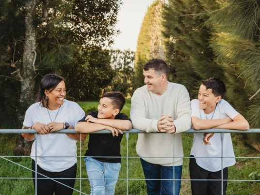 whanau standing behind a fence